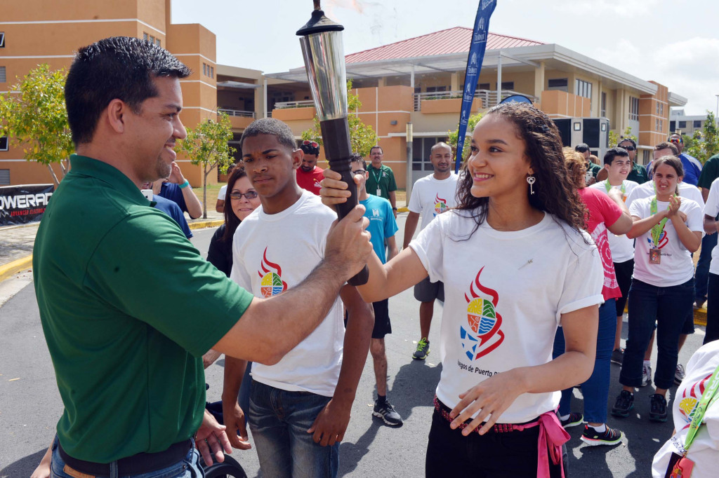 EL SECRETARIO DEL DRD, RAMÓN ORTA RECIBE LA ANTORCHA DE LOS SEGUNDOS JUEGOS DE PUERTO RICO, MANOS DE GRABIELA PADUA Y JOEL RUBIERA.